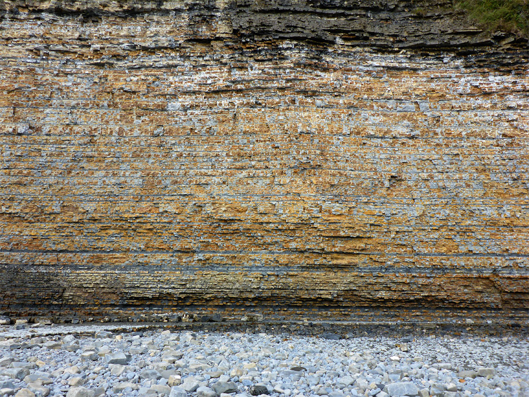 Pebbles below a thin-layered cliff