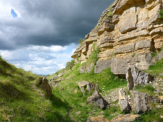 Grassy hollow below crumbling cliffs