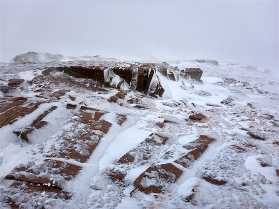 Ice on the reddish rocks at the summit of Cribyn